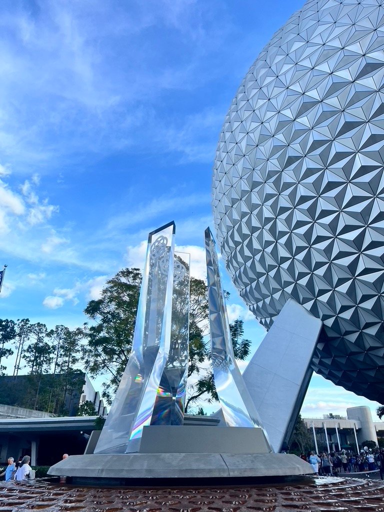 Glass statue and fountain next to side profile of Spaceship Earth in Epcot