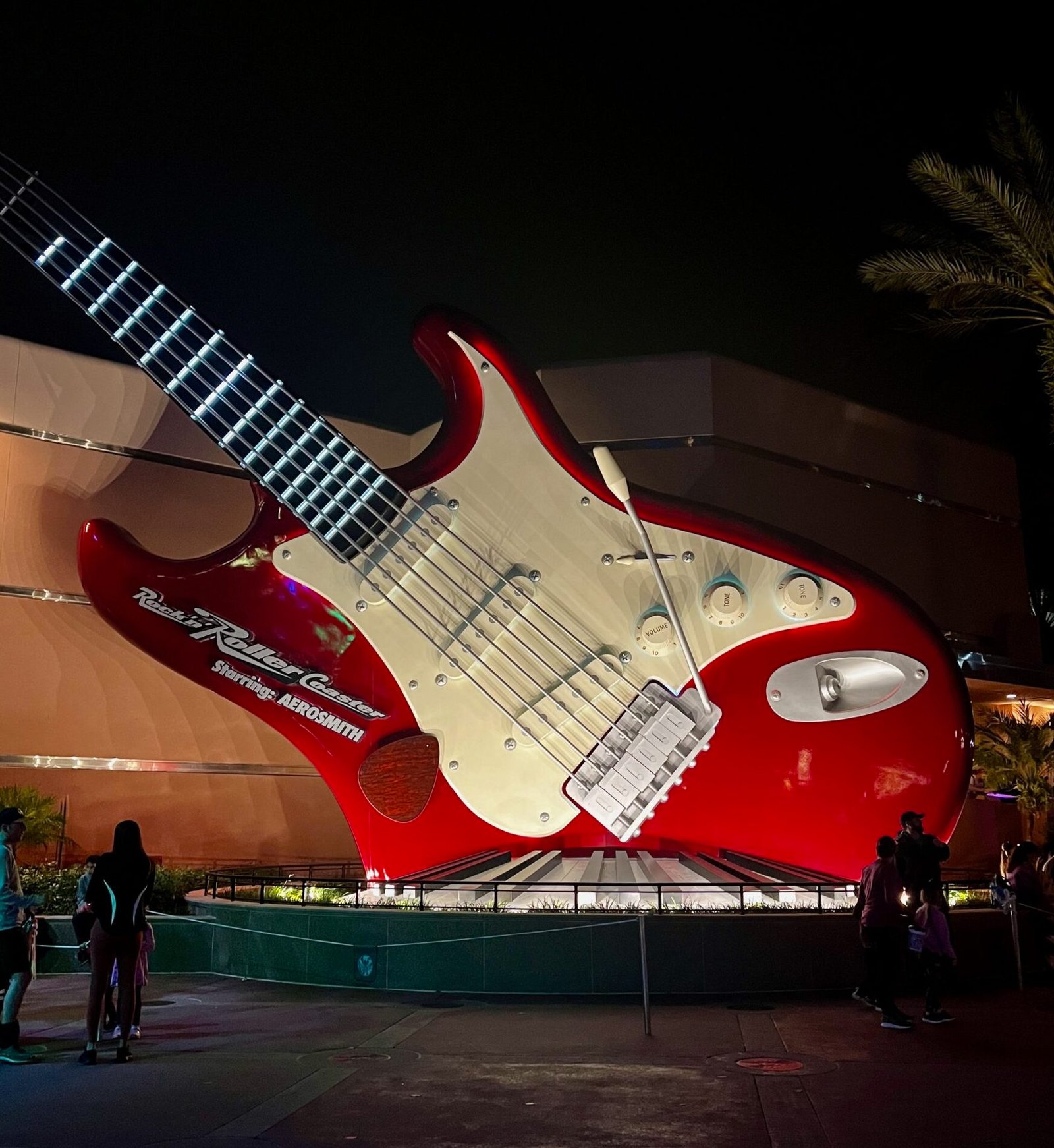 The red Rockin' Roller Coaster signature guitar aat the entrance to the attraction lit up at night in Disney's Hollywood Studios with minimal crowds. 