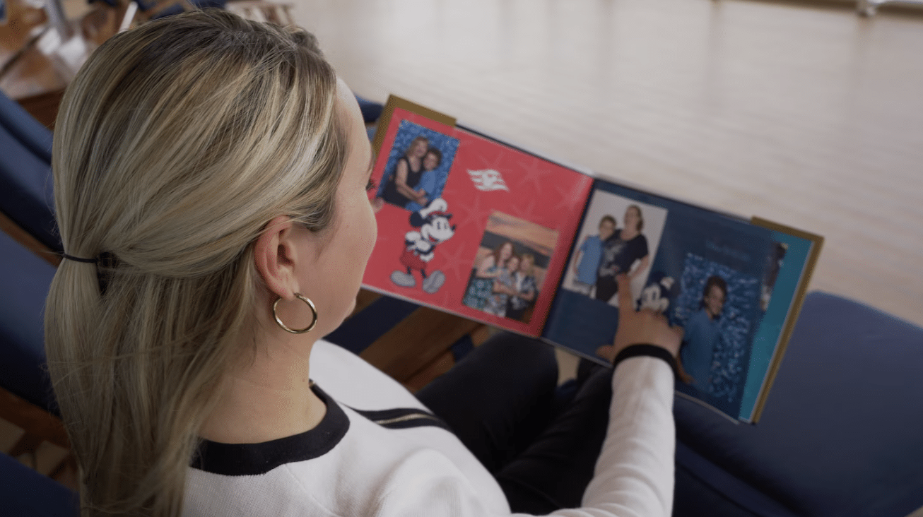 A woman is viewing her Photobook Keepsake from her Disney Cruise and the pictures taken with the Photo Package