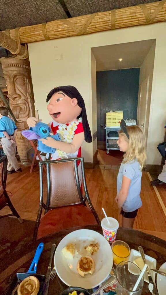 Young guest meets Lilo during a character breakfast at Walt Disney World’s ‘Ohana restaurant, as she shows off her plush Stitch, creating a fun and heartwarming Disney moment.