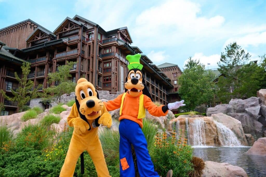 Pluto and Goofy posing together at the waterfall at Disney's Wilderness Lodge