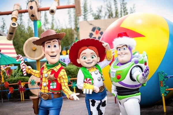 Image of Woody, Jessie, and Buzz from Toy Story posing in Toy Story Land in Hollywood Studios with their holiday outfits.