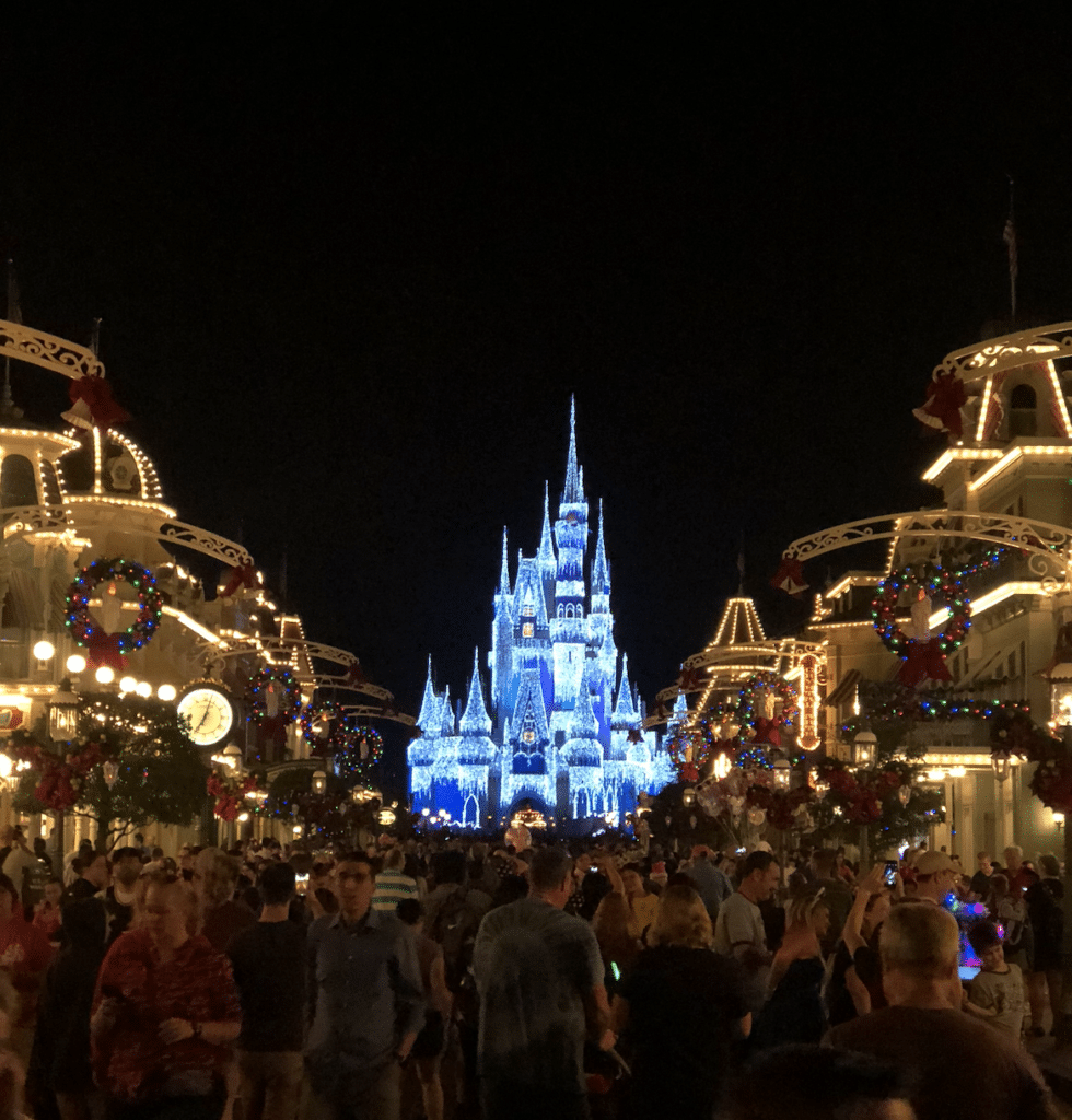 Picture of Magic Kingdom at night all decorated and lit up for the holidays with Christmas decorations and large crowds on Main Street U.S.A.