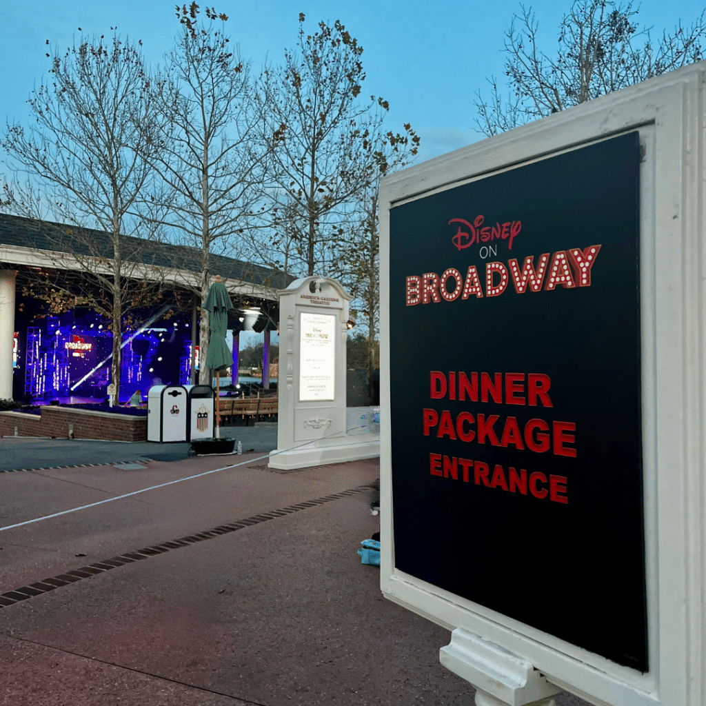 Image of the Disney on Broadway Dinner Package Entrance sign outside of the EPCOT amphitheater at dusk.