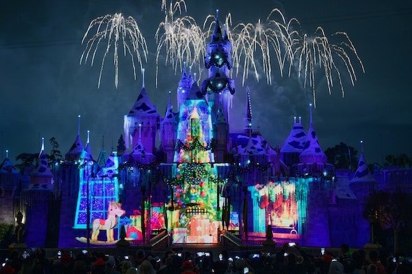 Wide shot of the Disneyland castle with the holiday fireworks and projections lighting it up at night for an evening showing.