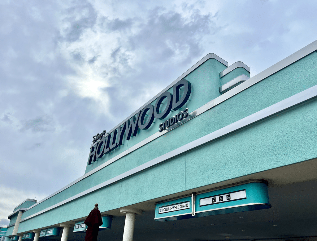 Wide-angle image of Disney's Hollywood Studios sign above the security check-point on a cloudy day.