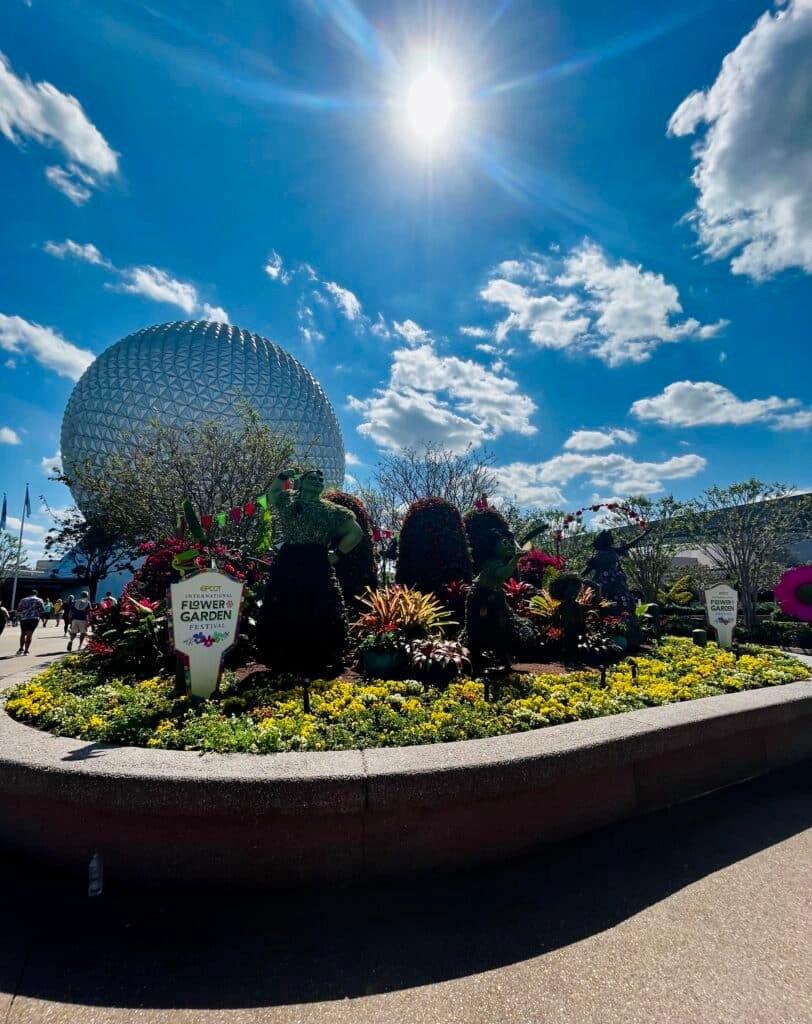 Encanto Topiary Entrance Display during EPCOT's International Flower and Garden Festival on a sunny day with the Space Ship Earth Icon in the Background