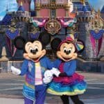 Disney teases Mickey and Minnie's colorful outfits for the 70th Anniversary Celebration in Disneyland and displayed behind them are all the 70th decorations draped over Sleeping Beauty castle.