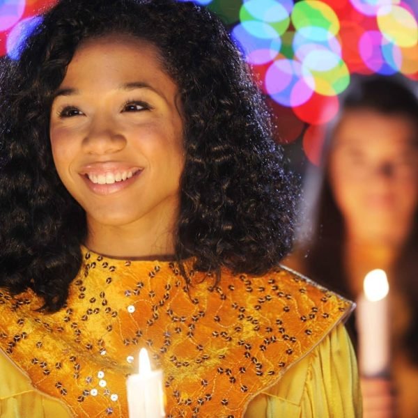 Disney stock image of a woman carrying a candle in her yellow and gold costume for the Candlelight Processional performance at EPCOT during the Festival of the Holidays